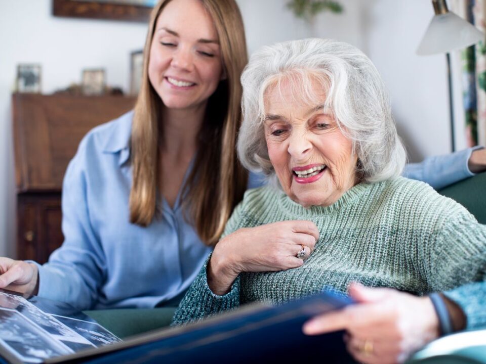 Elderly woman with photo album and aide