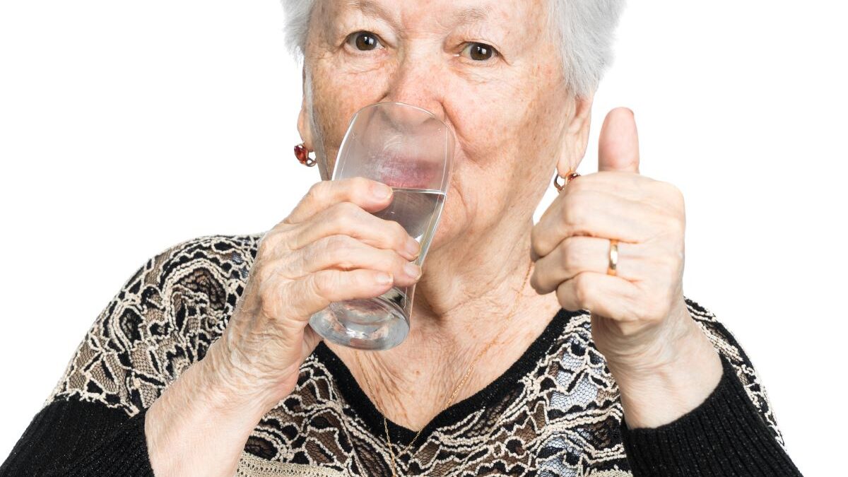 Elderly lady drinking water to prevent dehydration