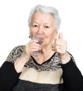 Elderly lady drinking water to prevent dehydration